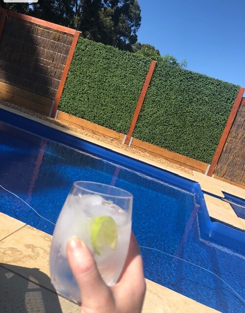 Premium Faux Boxwood Mat Installed Along a Pool Fence to Create an Entertaining Space
