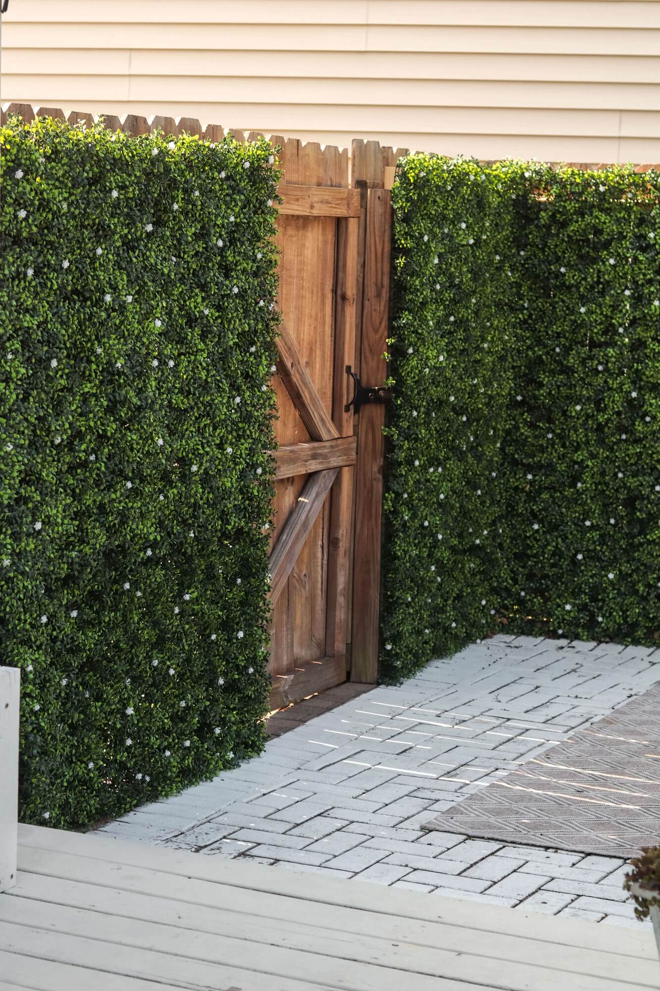 Artificial Boxwood Mat with Faux Flowers Installed Outdoors onto a Fence